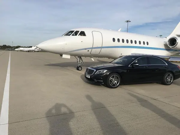Mercedes S Class beside a private jet on the airfield